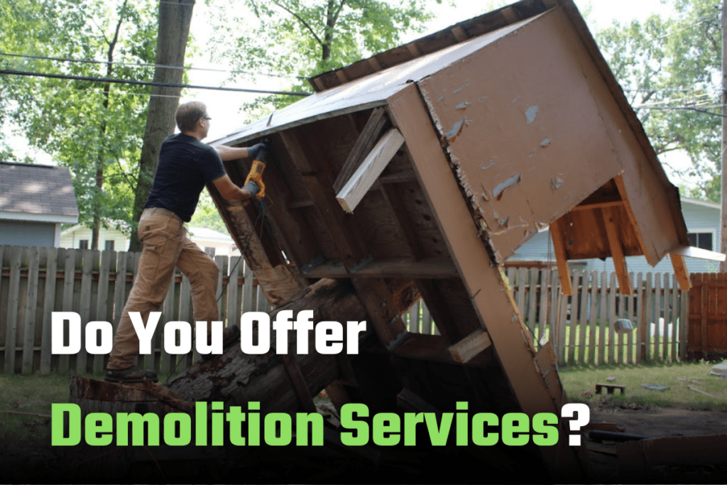 Ohio Junk Force worker in black shirt and khakis wields cordless demolition saw on a tilted wooden shed structure in backyard with fence and trees; green text asks "Do You Offer Demolition Services?"