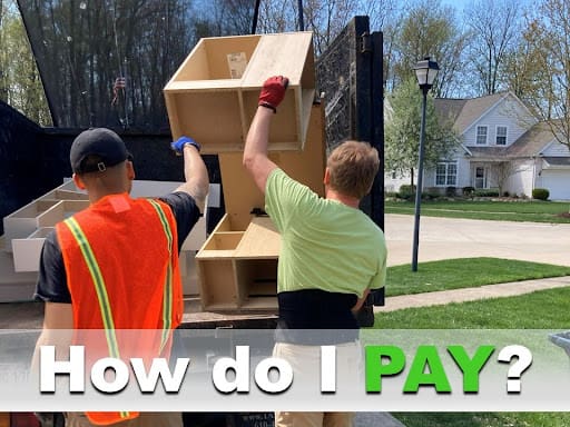 Two Ohio Junk Force workers in safety vests and gloves load wooden cabinets into dump truck outside suburban home; green text overlay asks "How do I PAY?" detailing payment for junk removal services.
