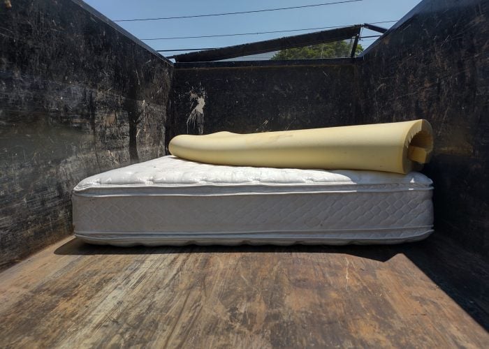 Used mattress and rolled foam topper placed inside a junk removal truck for haul-away service.